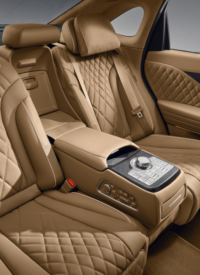 View of the back seat inside the Electrified G80. The quilted seats in a luxurious ecru camel monotone and the controller in the center are visible.