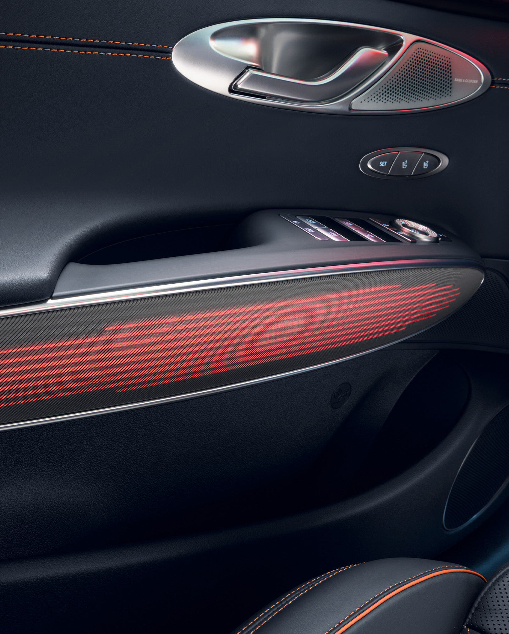 You can see the mood lighting in red on the interior door handle of the GV70 Sports Package. Above it are the door handle for opening and various control buttons.