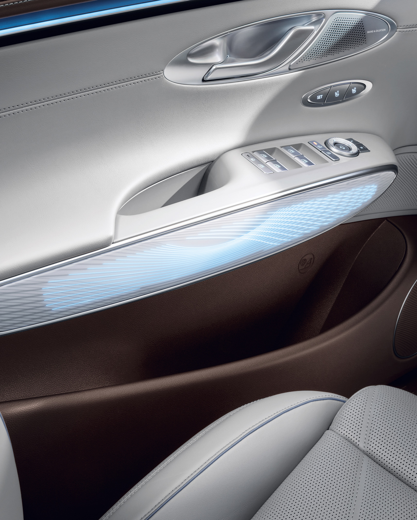 You can see the mood lighting in blue on the interior door handle of the GV70. Above it are the door handle for opening and various control buttons.